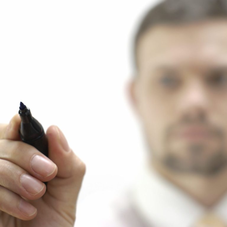 Ein Mann hält einen Stift und notiert Ergebnisse seines Coachings