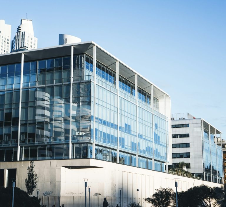 Moderne Bürogebäude mit großen Glasfenstern, umgeben von Stadtarchitektur.